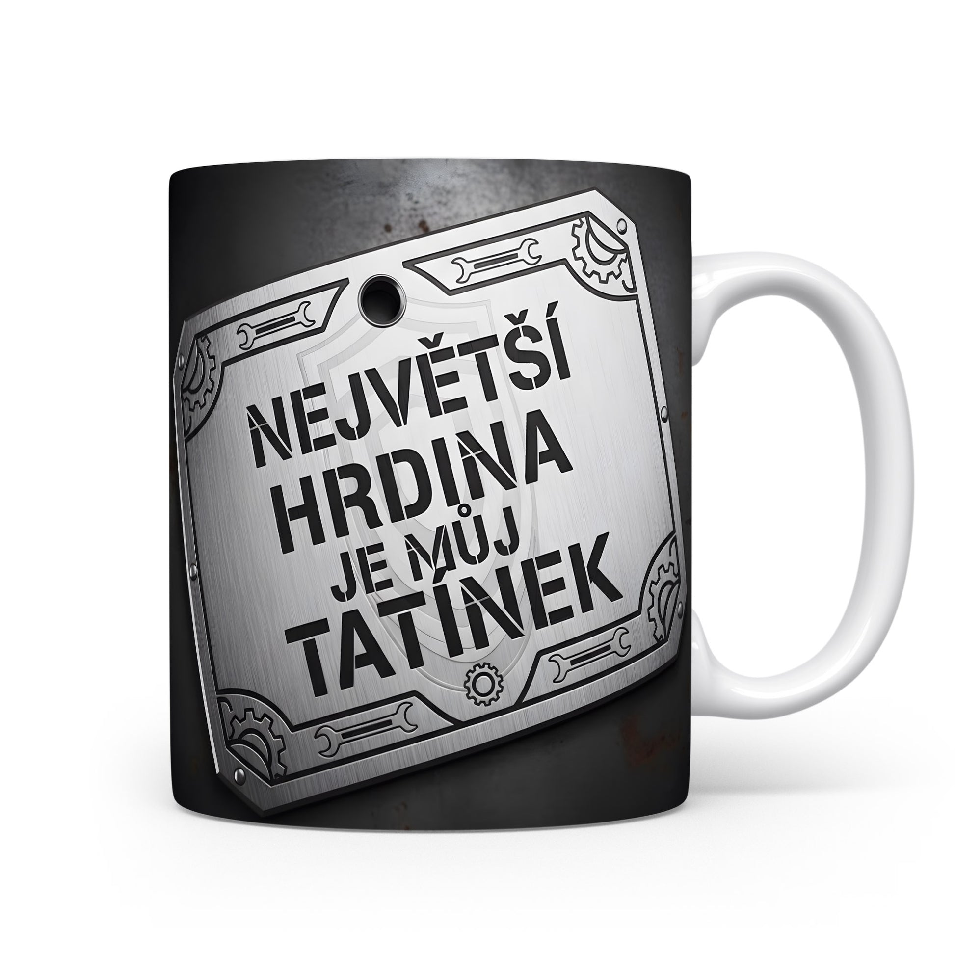 Černý hrnek s kovovým štítem a nápisem 'NEJVĚTŠÍ HRDINA JE MŮJ TATÍNEK'.