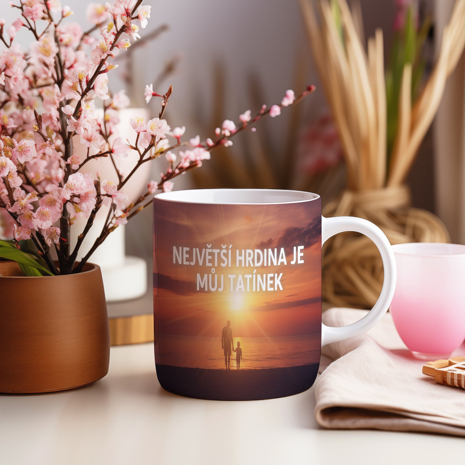 Hrnek s nápisem a siluetou otce a dítěte při západu slunce.