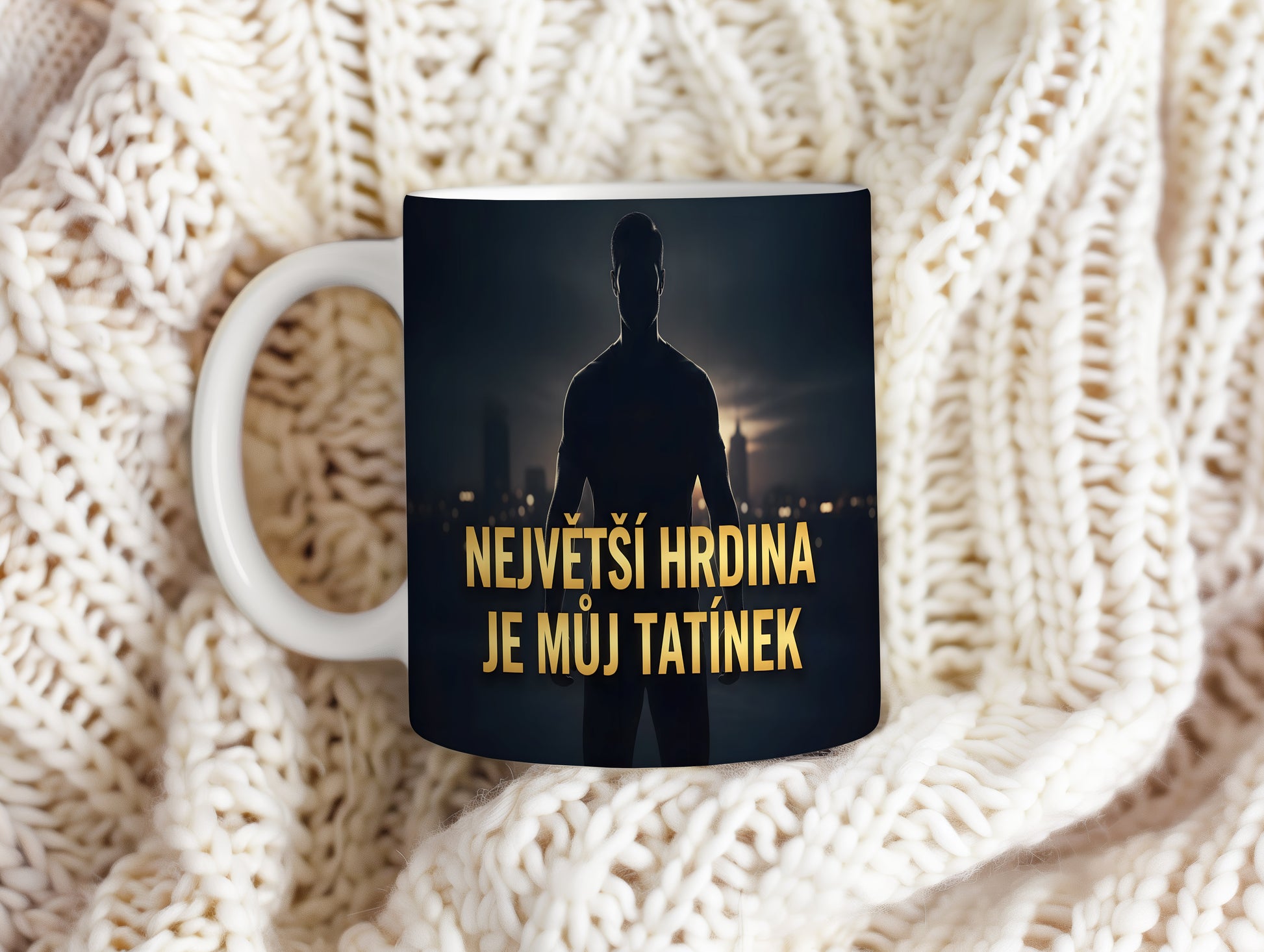 Hrnek s nápisem NEJVĚTŠÍ HRDINA JE MŮJ TATÍNEK a siluetou muže na pozadí města.