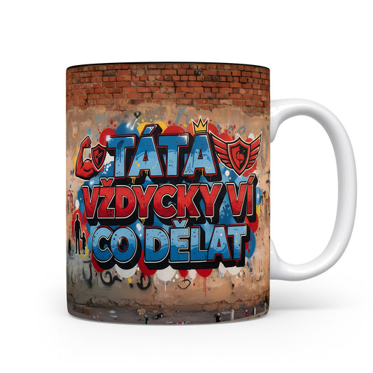 Hrnek s nápisem TÁTA VŽDYCKY VÍ CO DĚLAT na cihlové zdi s grafitti.