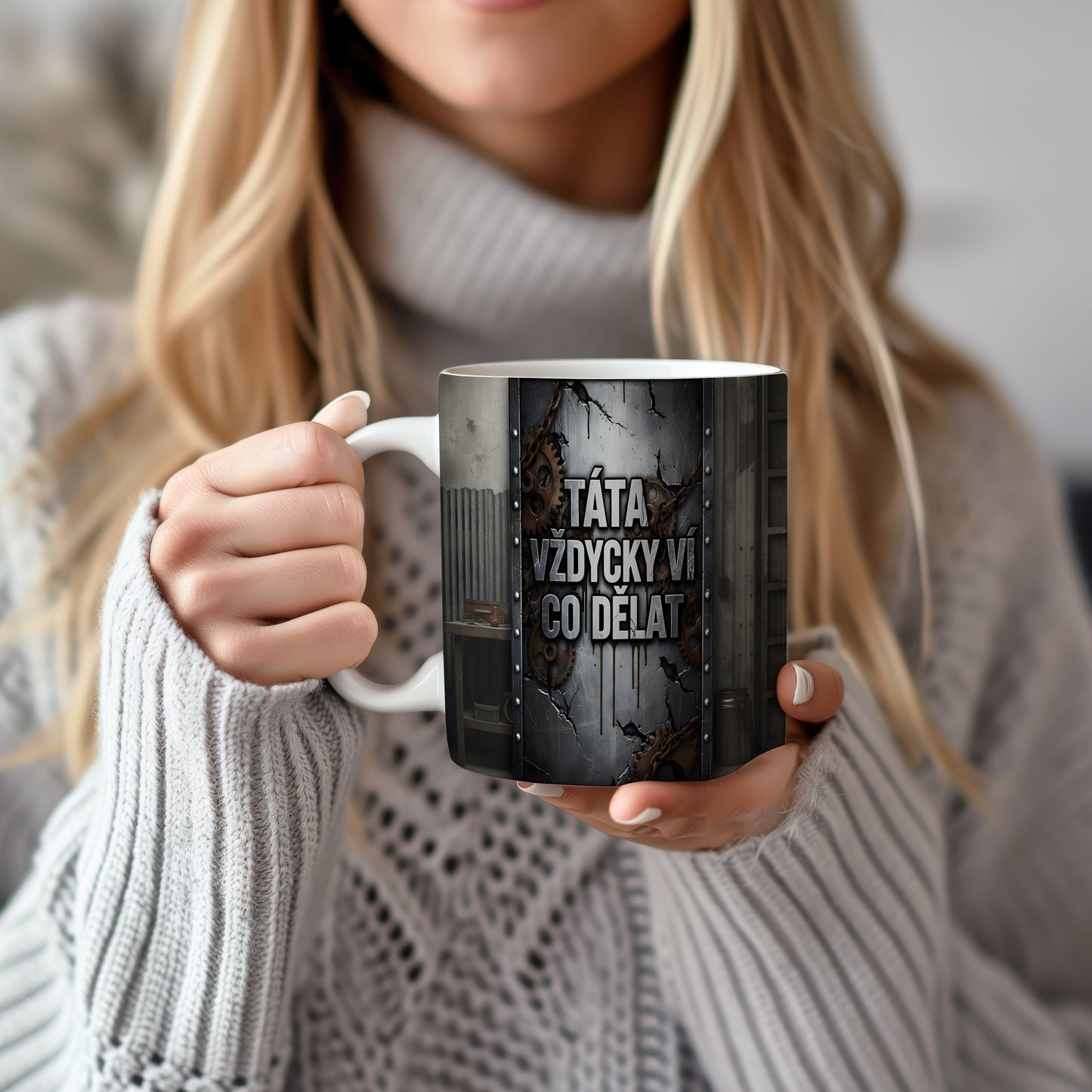 Hrnek s nápisem 'TÁTA VŽDYCKY VÍ CO DĚLAT' a ozubenými koly na kovovém pozadí.