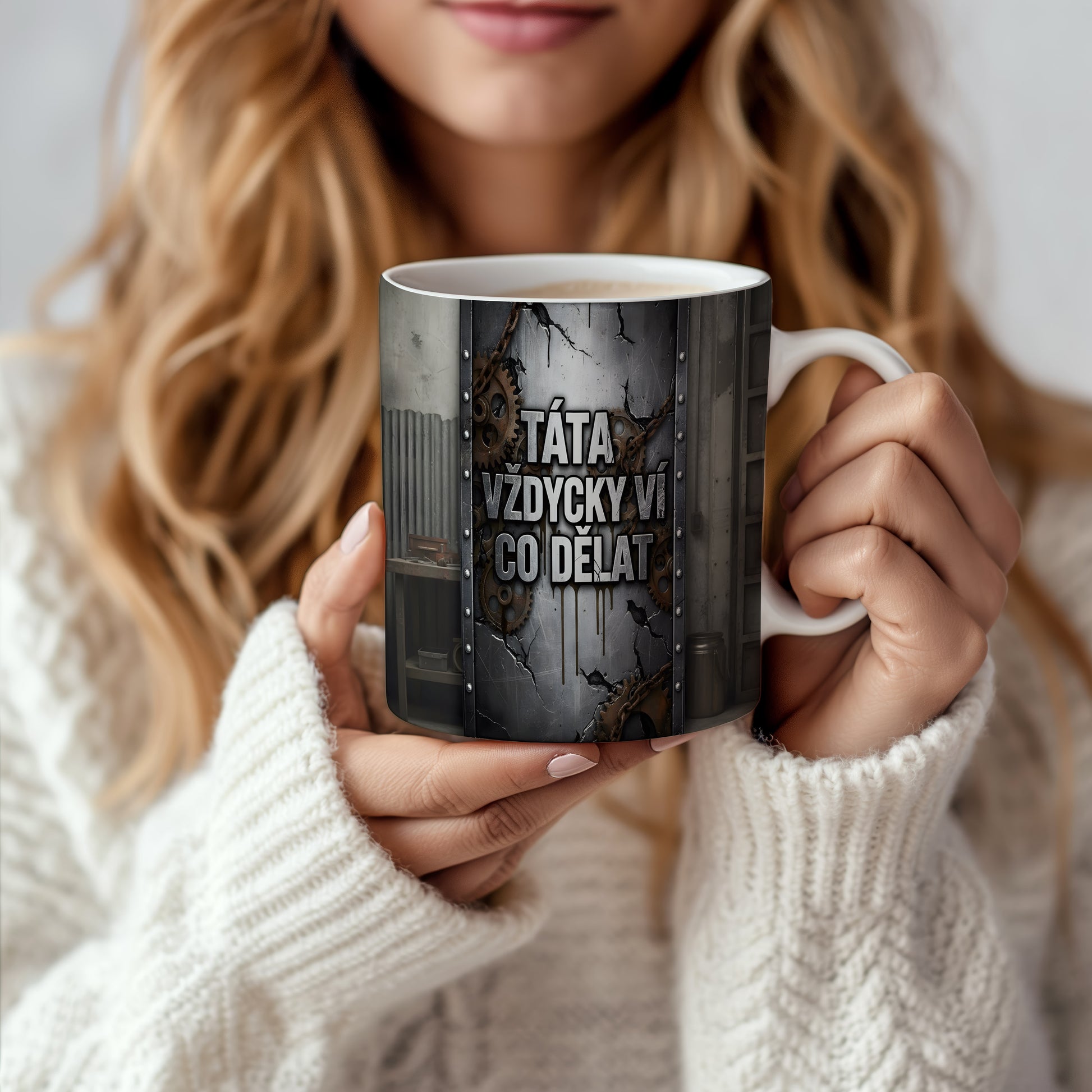 Hrnek s nápisem 'TÁTA VŽDYCKY VÍ CO DĚLAT' a ozubenými koly na kovovém pozadí.