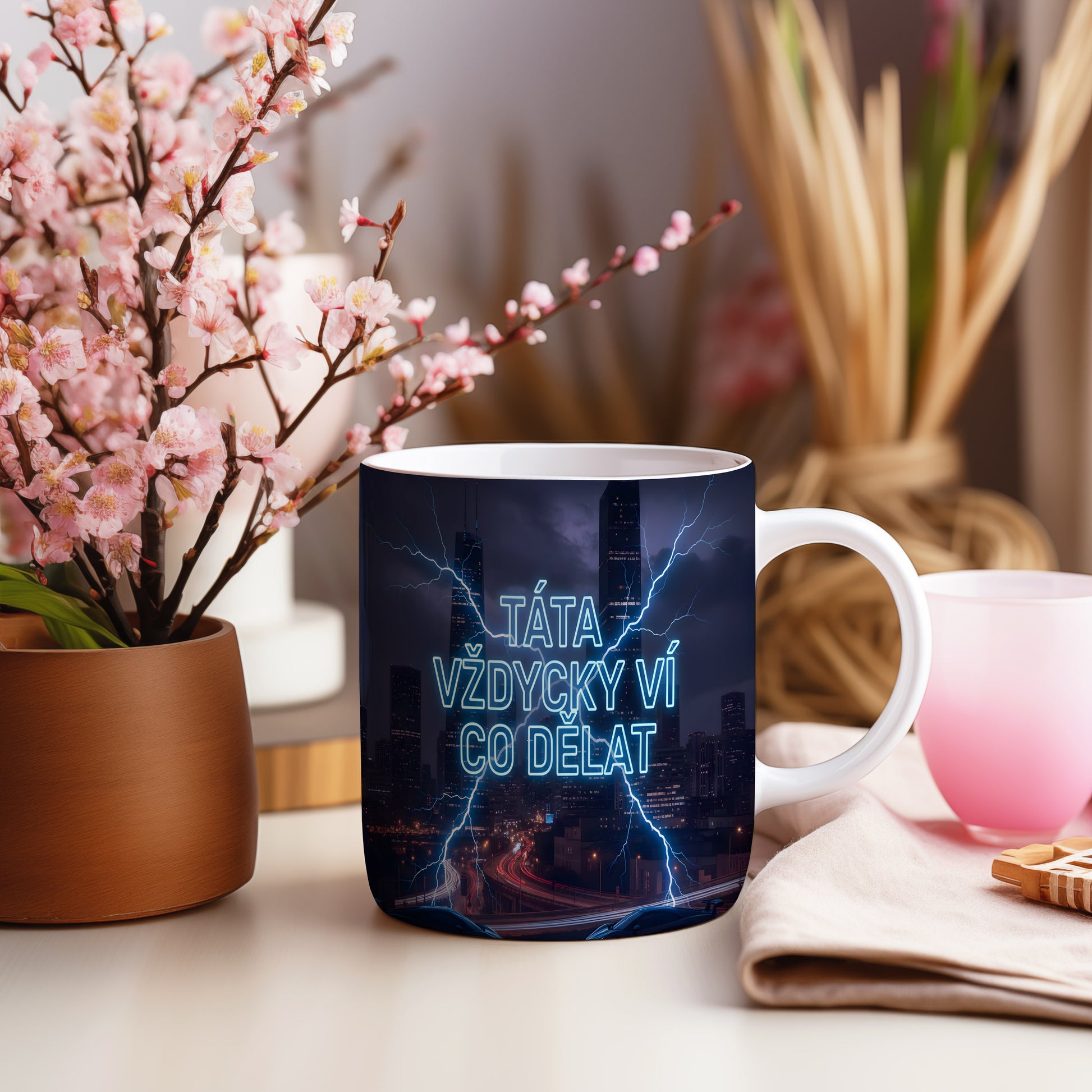Hrnek s nápisem 'TÁTA VŽDYCKY VÍ CO DĚLAT' a blesky na pozadí města.
