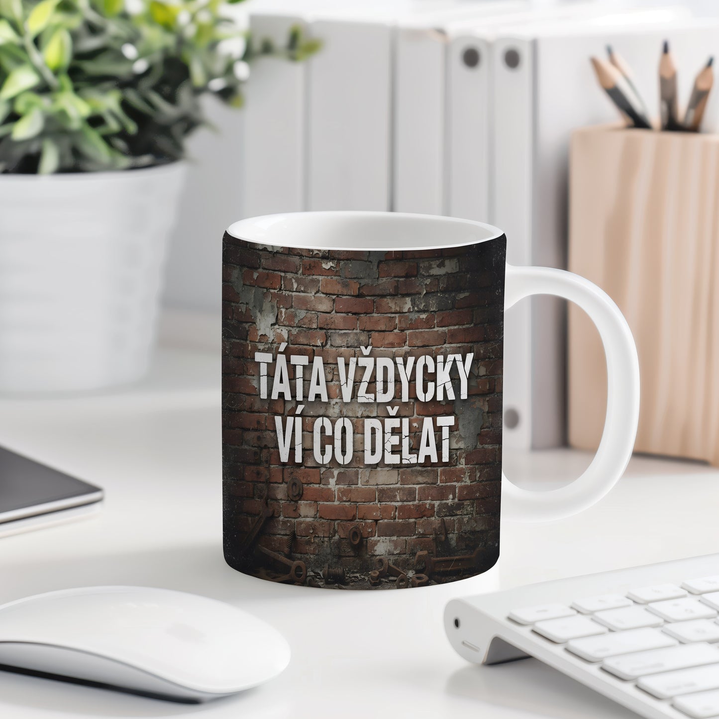 Hrnek s nápisem 'TÁTA VŽDYCKY VÍ CO DĚLAT' na cihlovém pozadí.