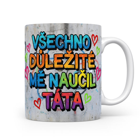 Hrnek s barevným nápisem a srdíčky na betonovém pozadí.