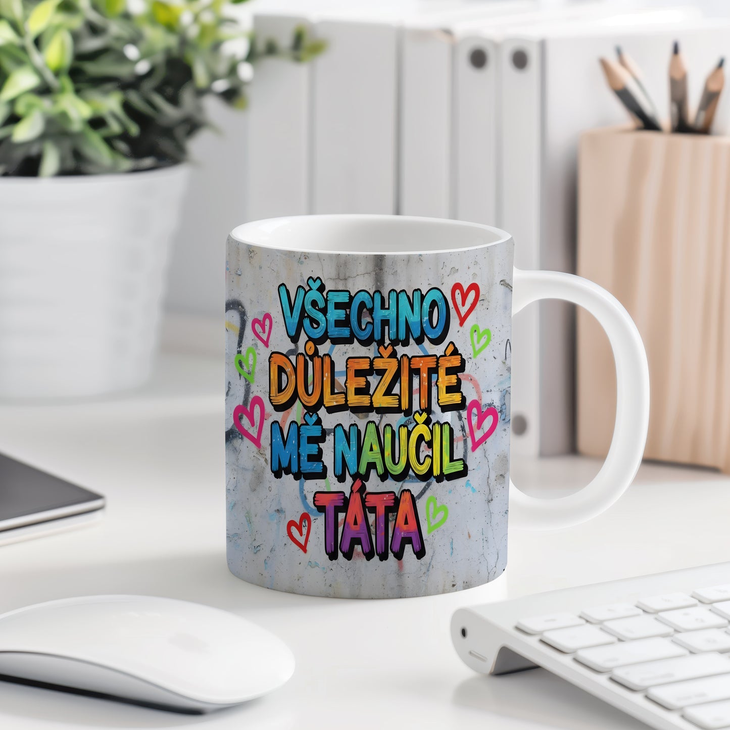 Hrnek s barevným nápisem a srdíčky na betonovém pozadí.