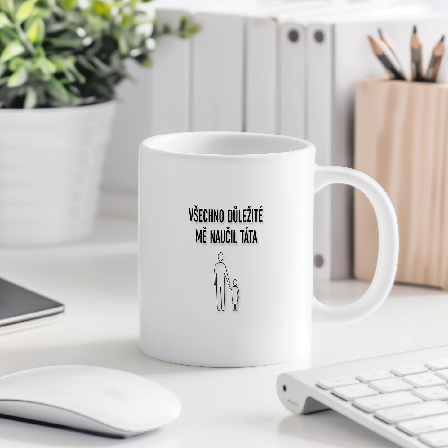 Bílý hrnek s černým nápisem a minimalistickými postavami.