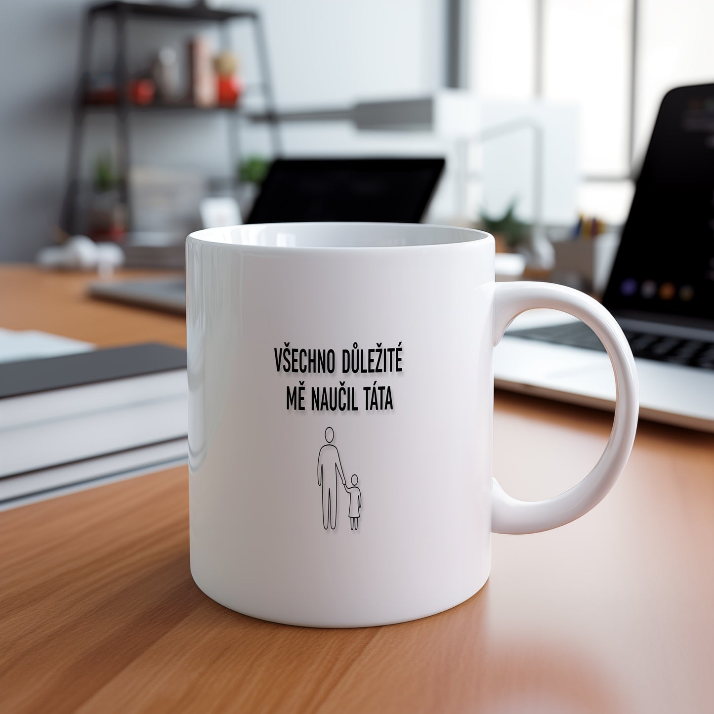 Bílý hrnek s černým nápisem a minimalistickými postavami.