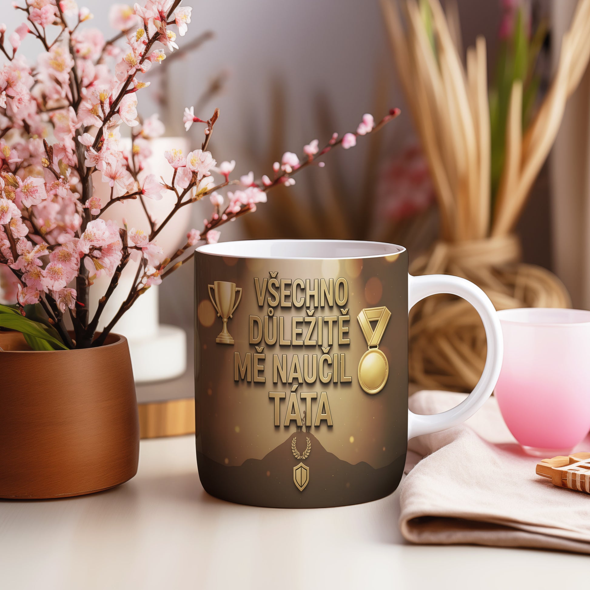 Hrnek se zlatými trofejemi a nápisem VŠECHNO DŮLEŽITÉ MĚ NAUČIL TÁTA.