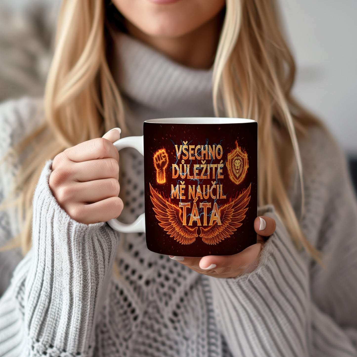 Černý hrnek s oranžovými motivy křídel, pěsti a lva.