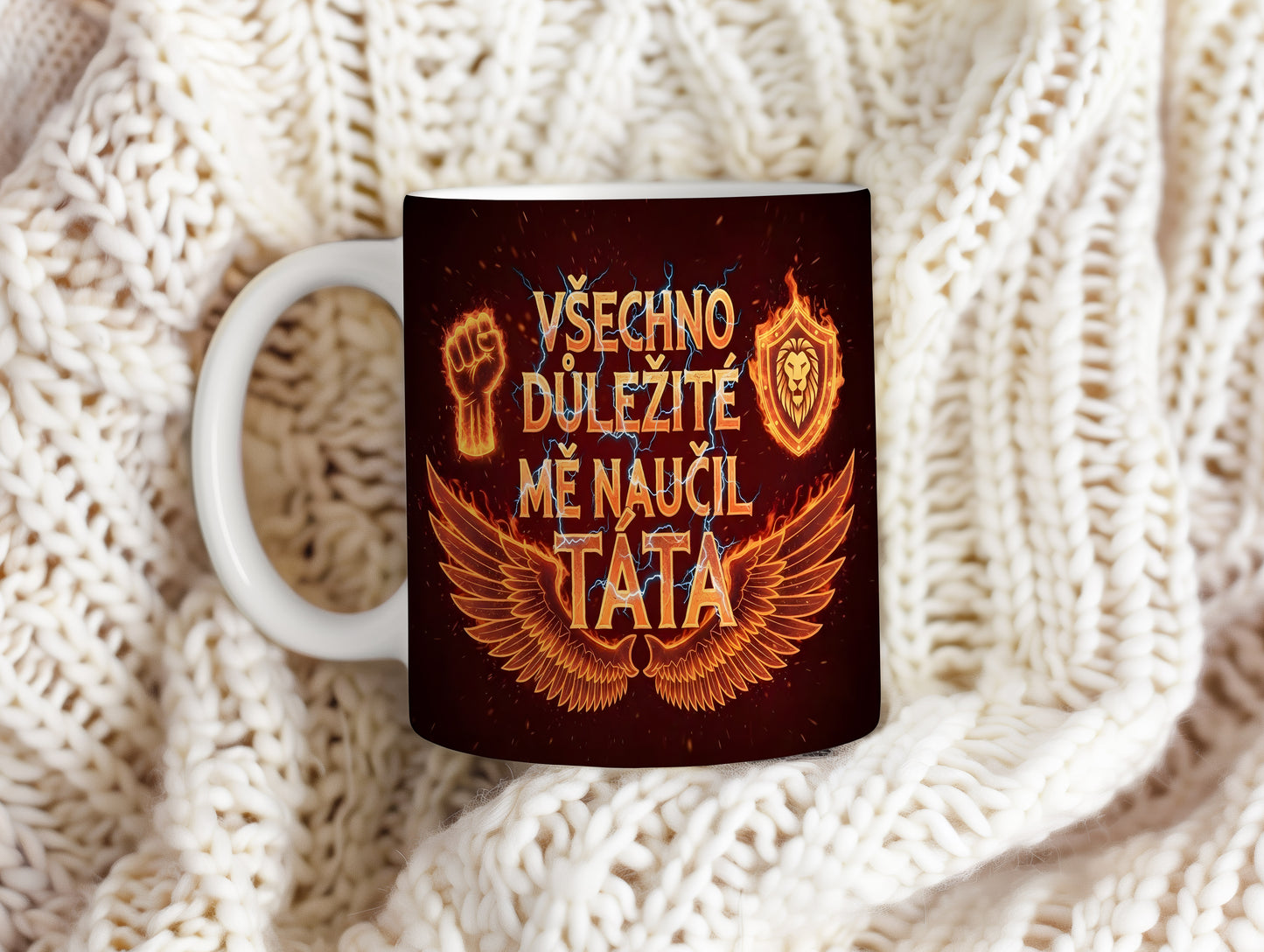 Černý hrnek s oranžovými motivy křídel, pěsti a lva.