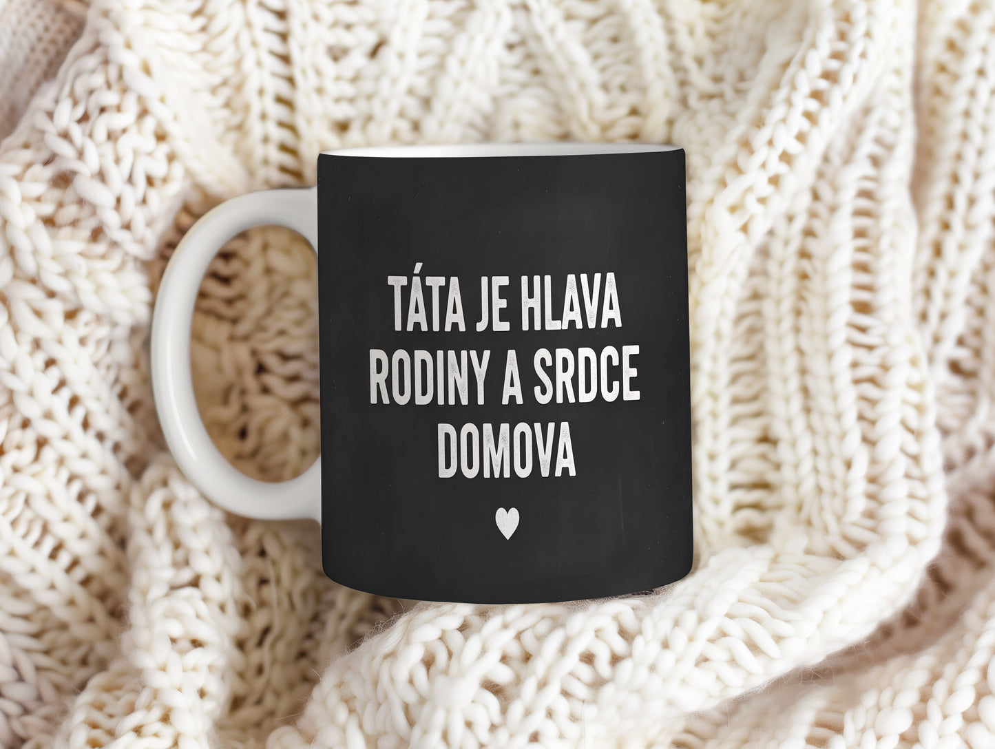 Černý hrnek s bílým nápisem TÁTA JE HLAVA RODINY A SRDCE DOMOVA a malým srdcem.