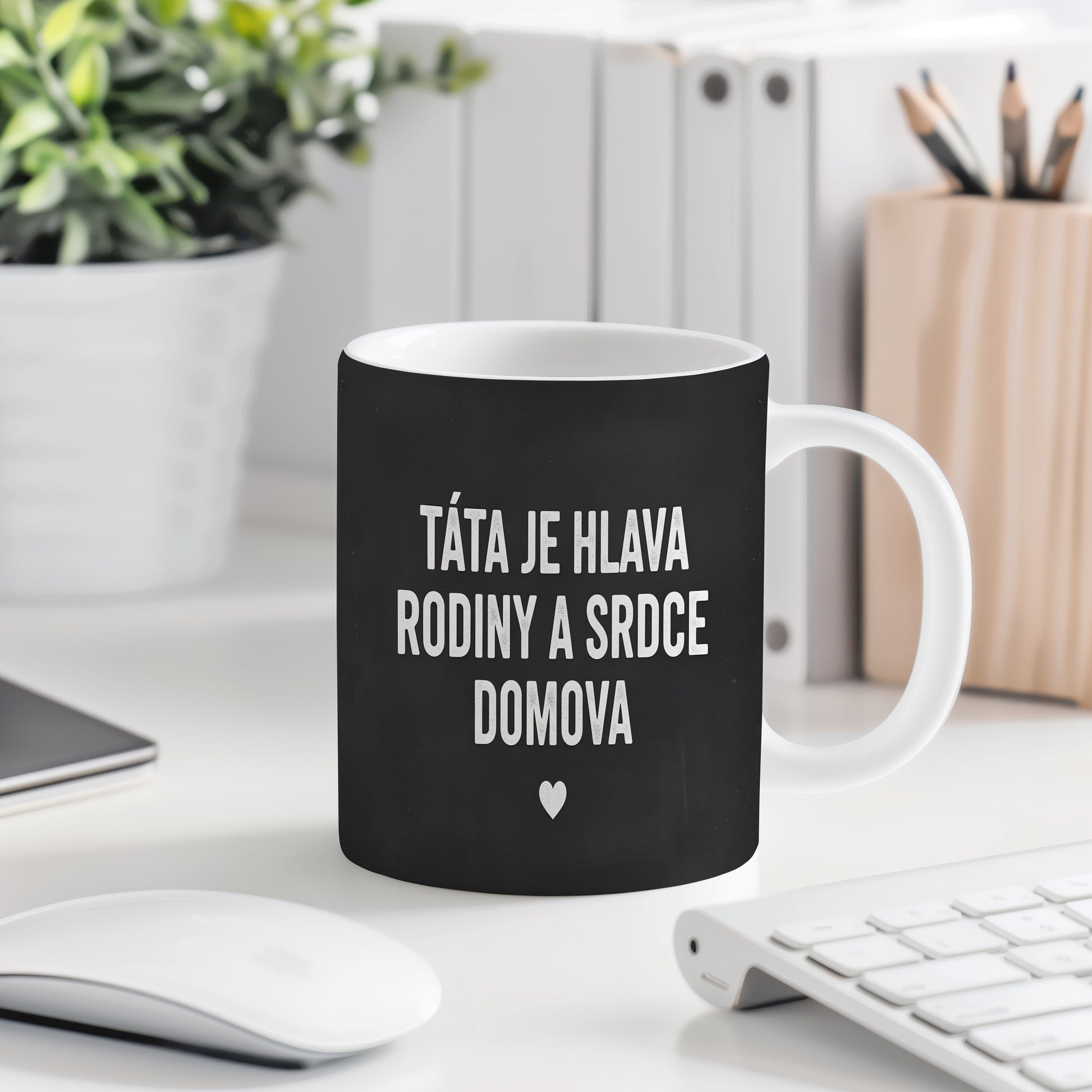 Černý hrnek s bílým nápisem TÁTA JE HLAVA RODINY A SRDCE DOMOVA a malým srdcem.