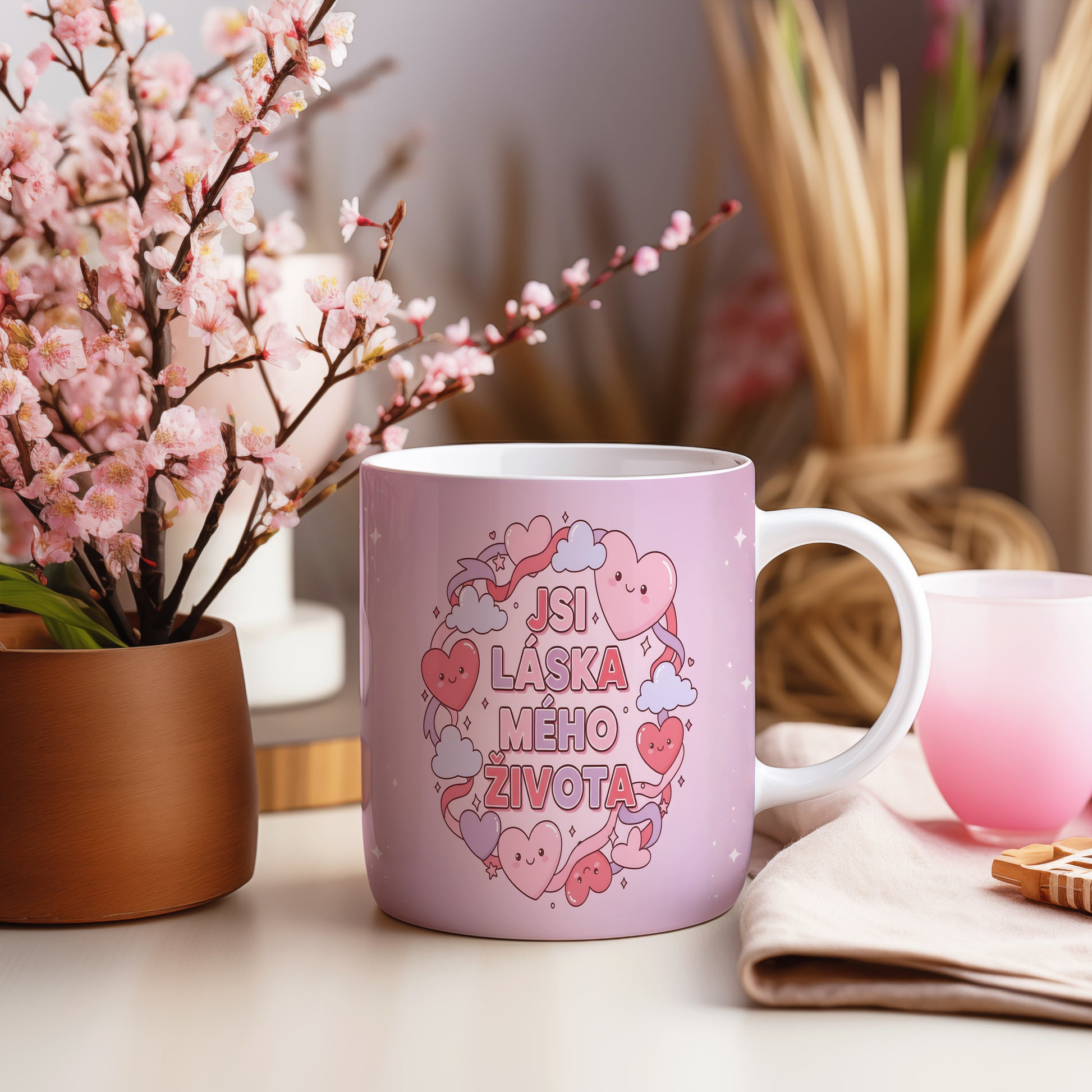 Růžový hrnek s nápisem JSI LÁSKA MÉHO ŽIVOTA a motivem srdcí.