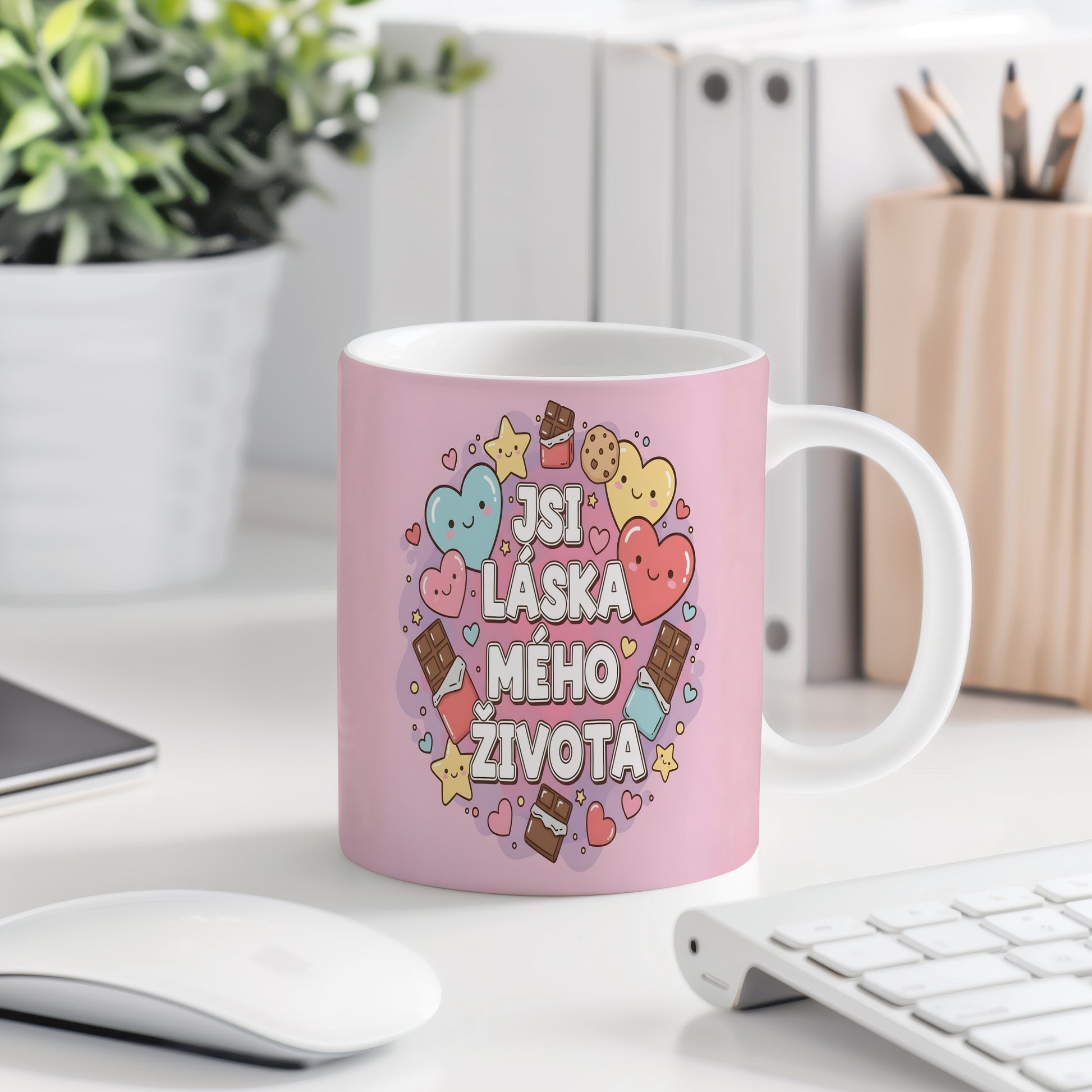 Růžový hrnek s nápisem 'JSI LÁSKA MÉHO ŽIVOTA' a motivy srdcí a sladkostí.