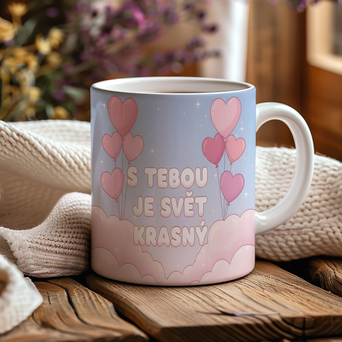 Hrnek s růžovými srdci a nápisem S tebou je svět krásný na pastelovém pozadí.