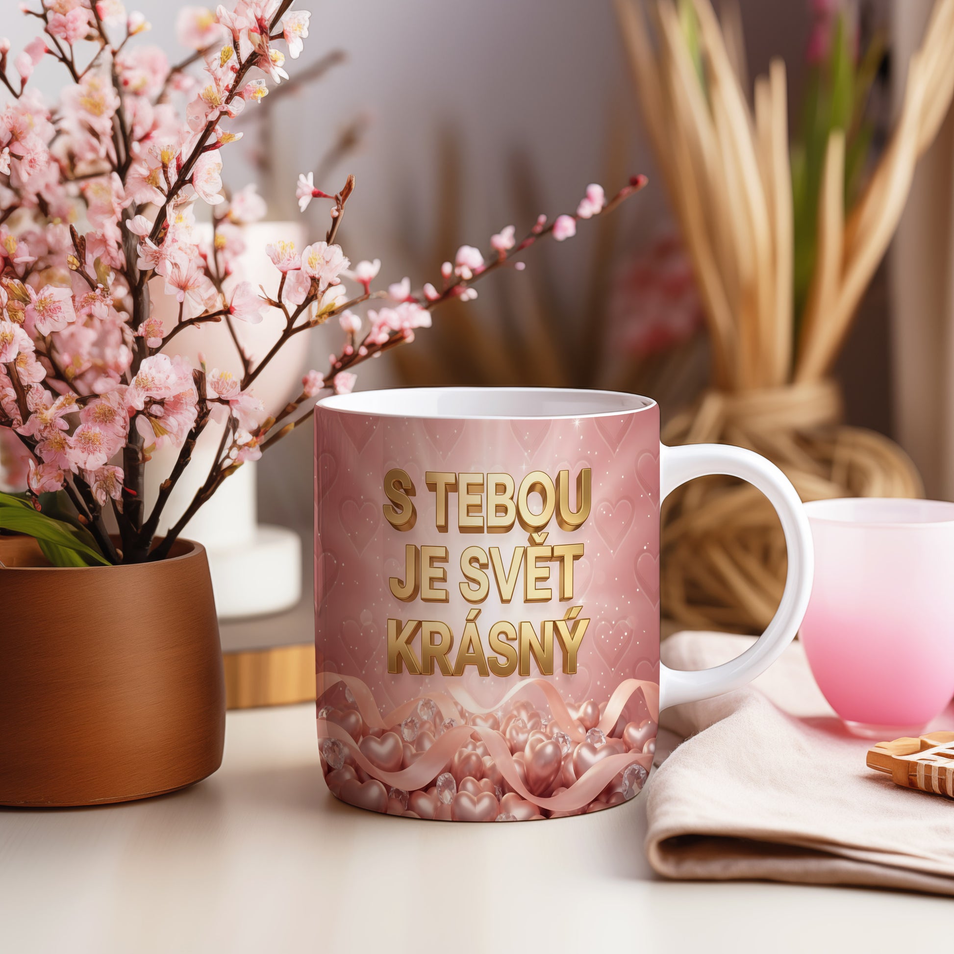 Růžový hrnek se zlatým nápisem a srdíčky.