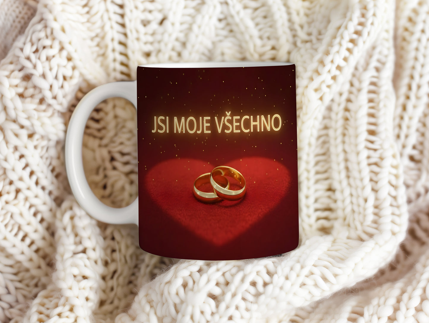 Červený hrnek s nápisem JSI MOJE VŠECHNO a zlatými prsteny na sametovém srdci.