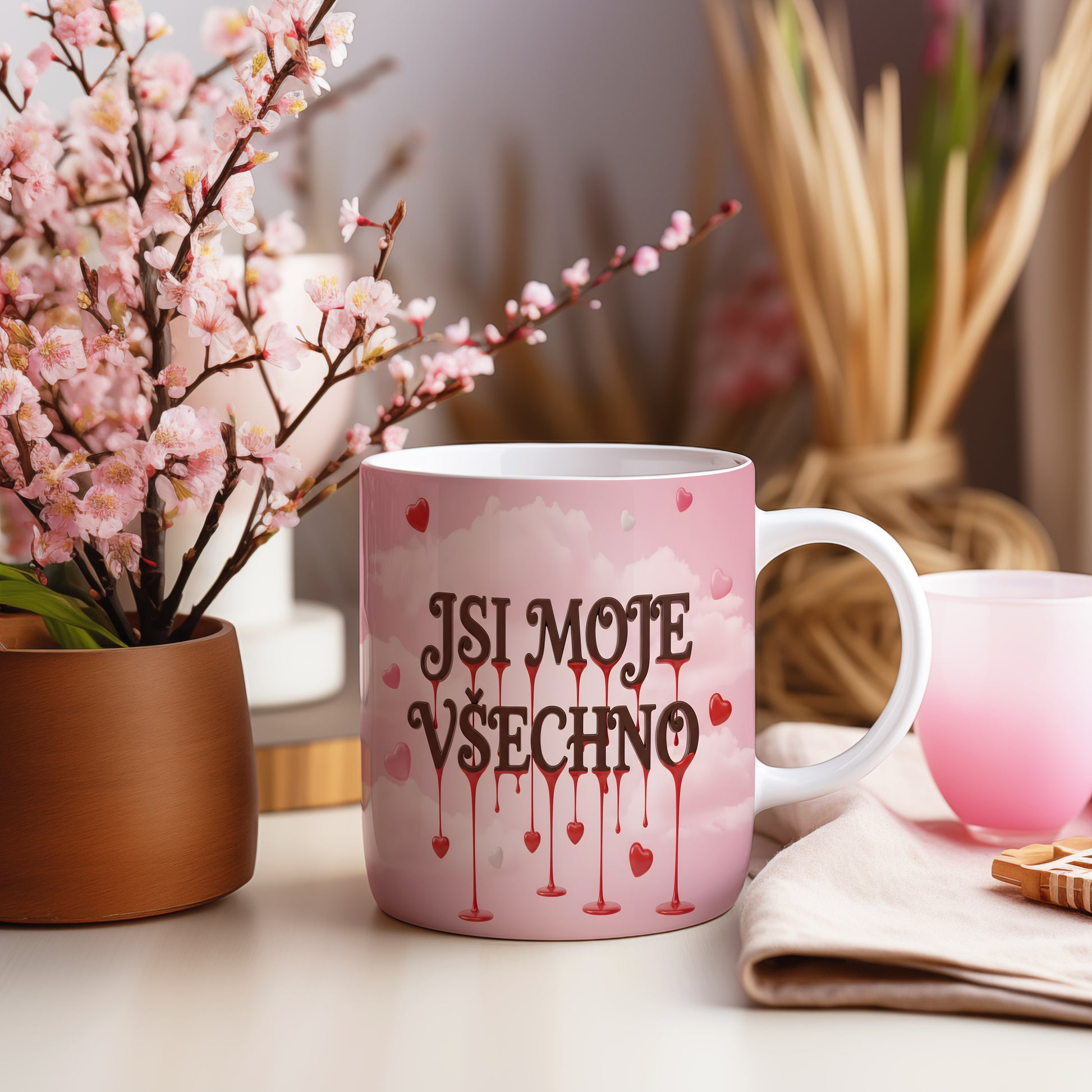 Růžový hrnek s nápisem JSI MOJE VŠECHNO a motivem srdcí.