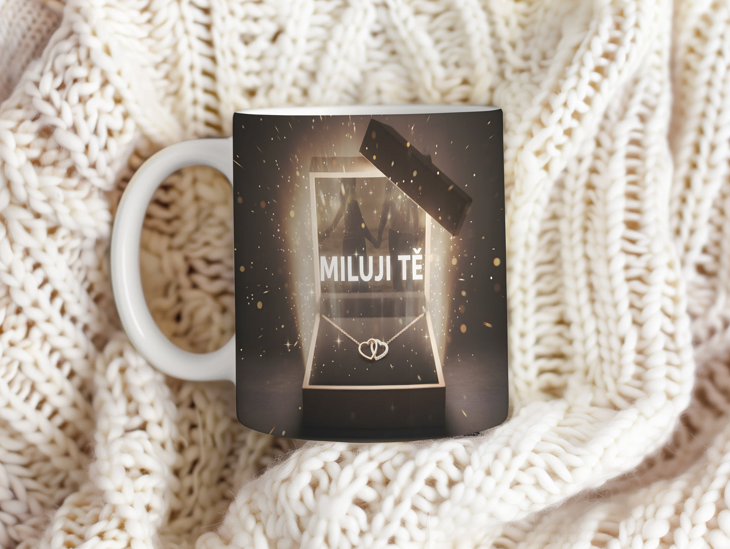 Hrnek s nápisem MILUJI TĚ a zlatými třpytkami na tmavém pozadí.