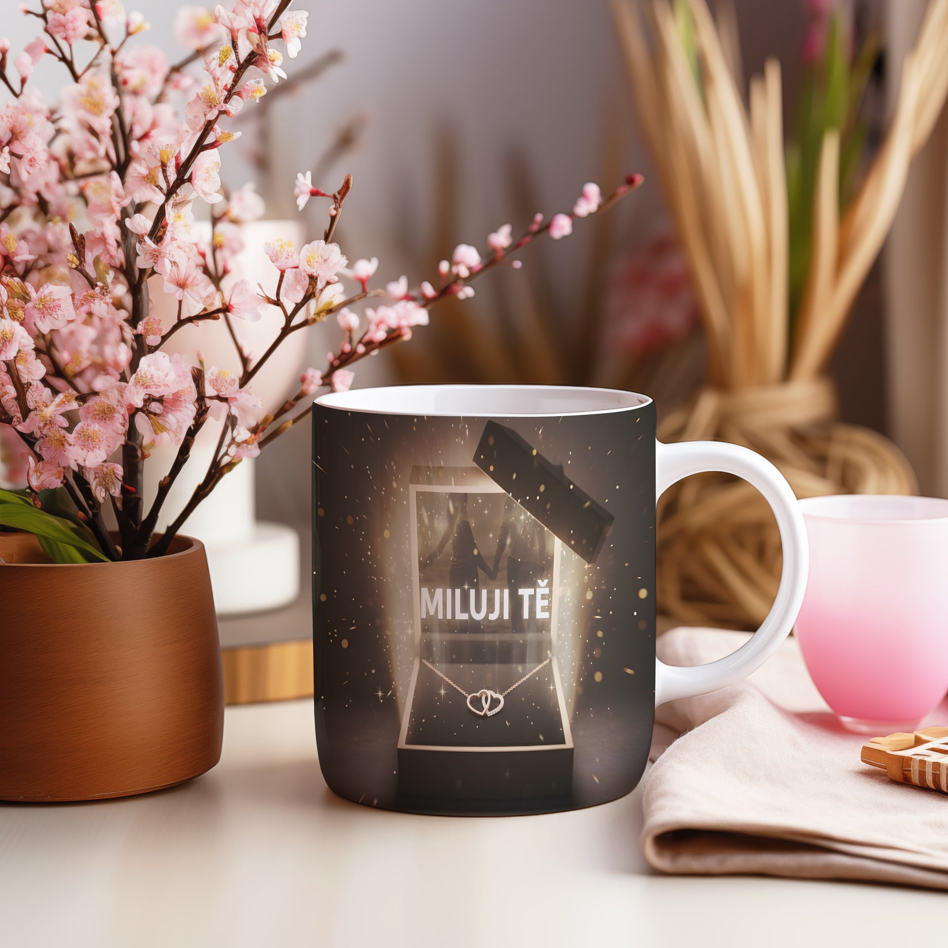 Hrnek s nápisem MILUJI TĚ a zlatými třpytkami na tmavém pozadí.