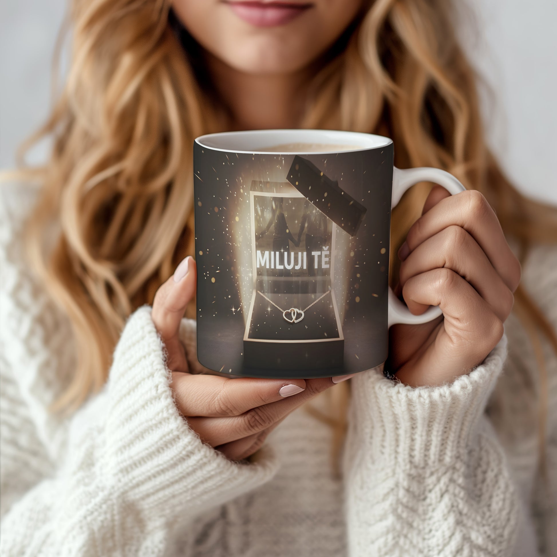 Hrnek s nápisem MILUJI TĚ a zlatými třpytkami na tmavém pozadí.