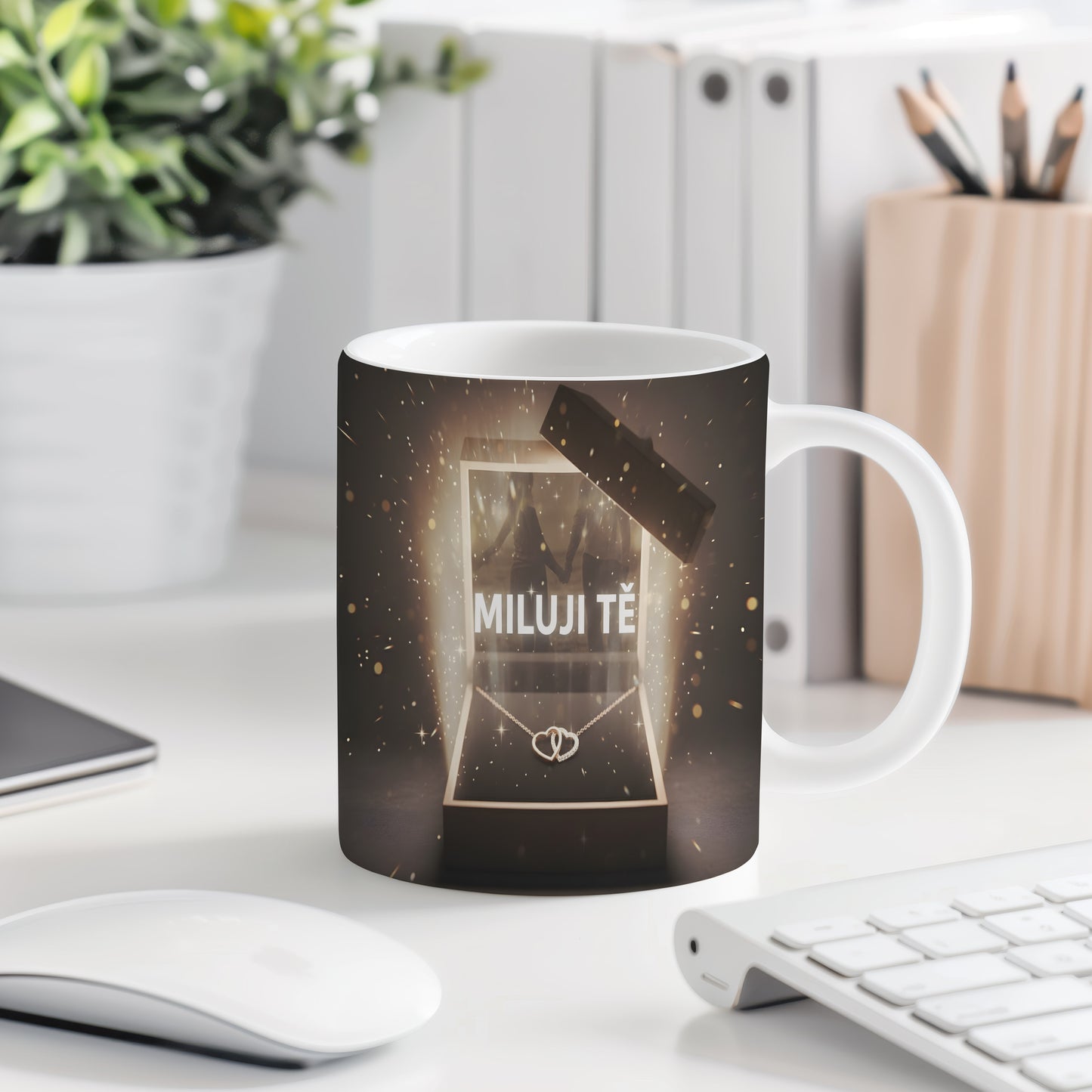 Hrnek s nápisem MILUJI TĚ a zlatými třpytkami na tmavém pozadí.