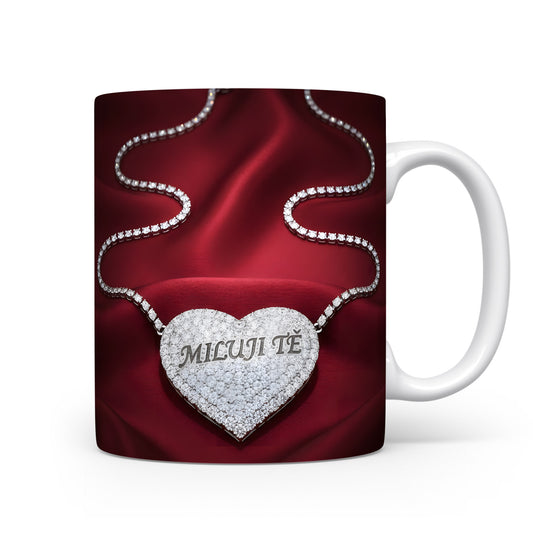 Bílý hrnek s červeným saténovým pozadím a diamantovým srdcem s nápisem MILUJI TĚ.