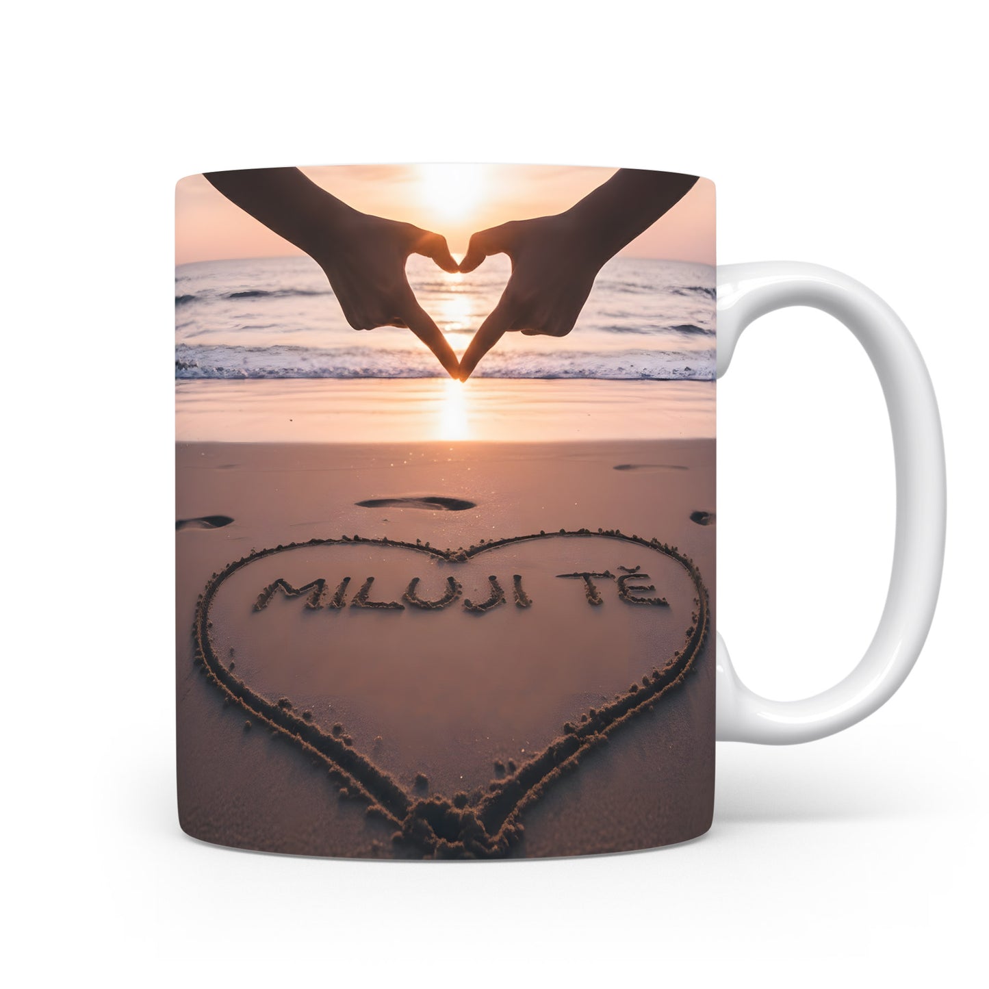 Hrnček s nápisem MILUJI TĚ na pláži při západu slunce.