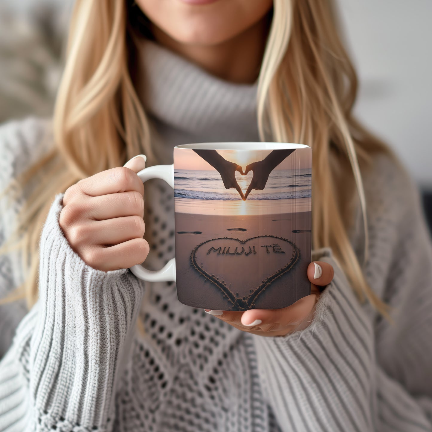 Hrnček s nápisem MILUJI TĚ na pláži při západu slunce.