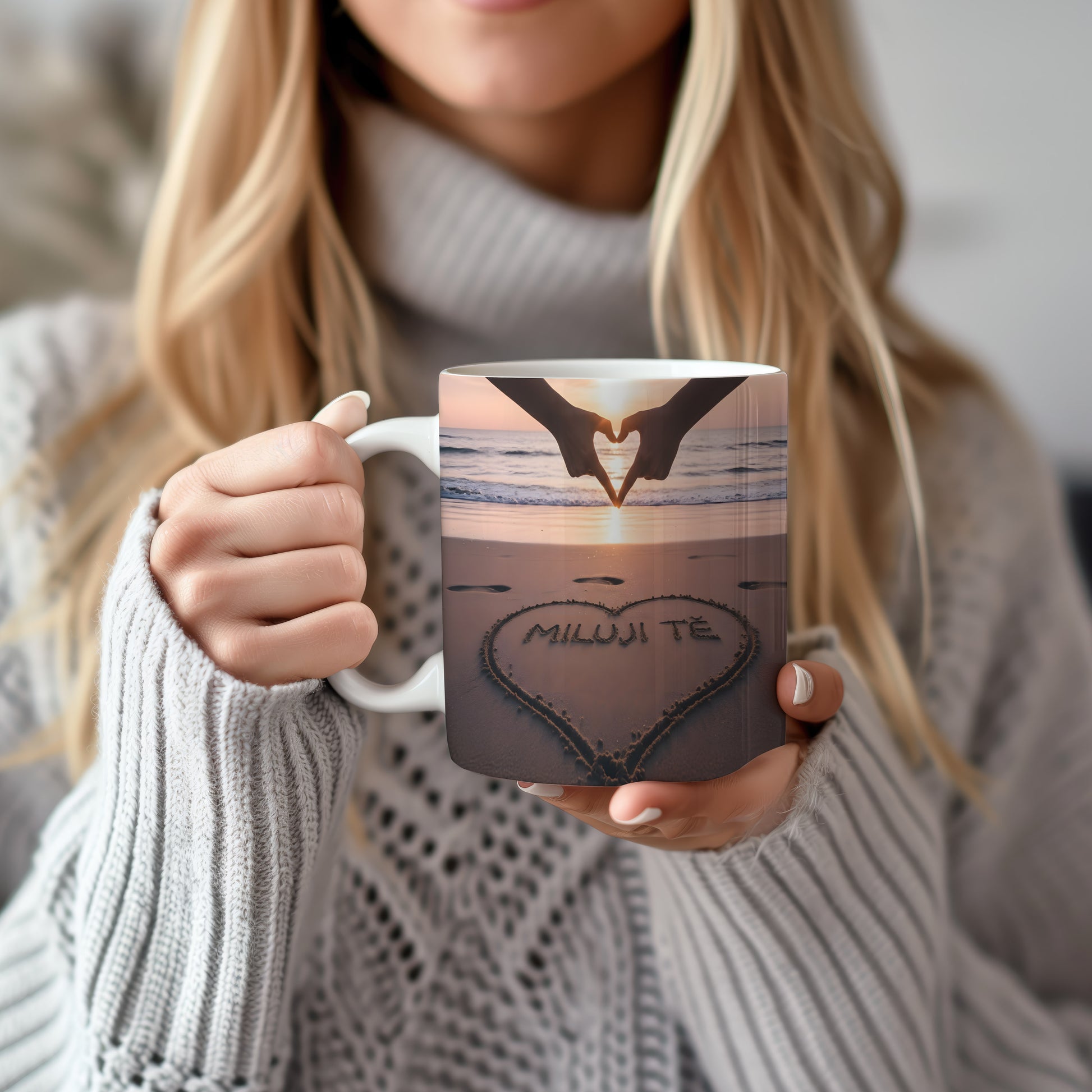Hrnček s nápisem MILUJI TĚ na pláži při západu slunce.