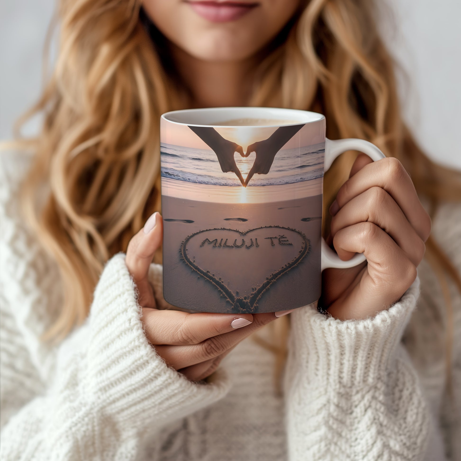 Hrnček s nápisem MILUJI TĚ na pláži při západu slunce.