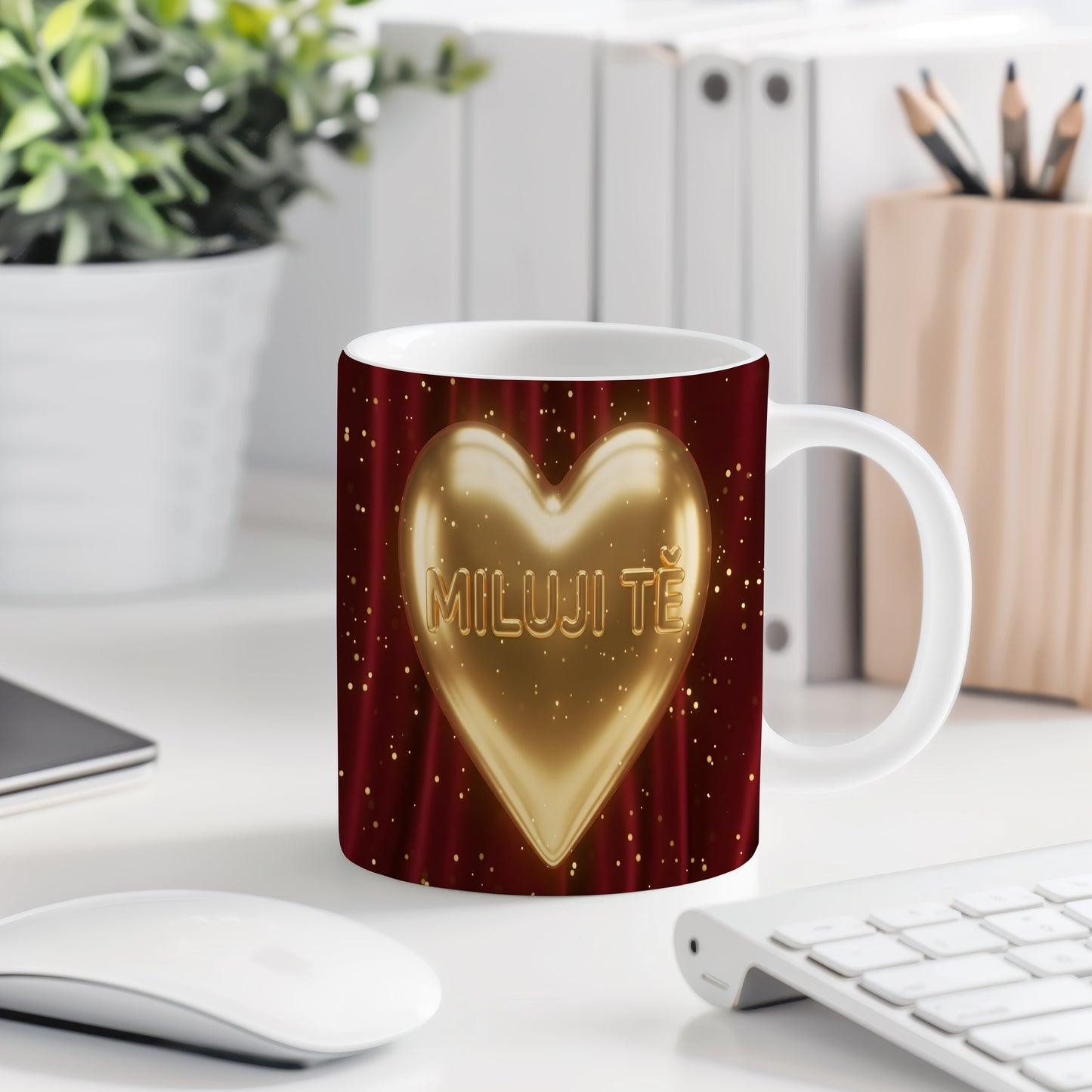 Hrnek s nápisem MILUJI TĚ a zlatým srdcem na červeném pozadí.