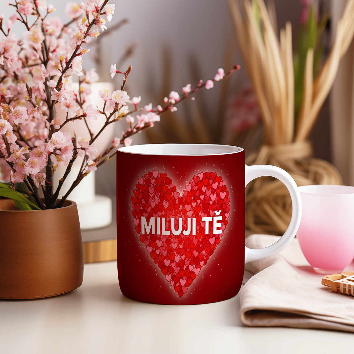 Červený hrnek s nápisem MILUJI TĚ a srdci.