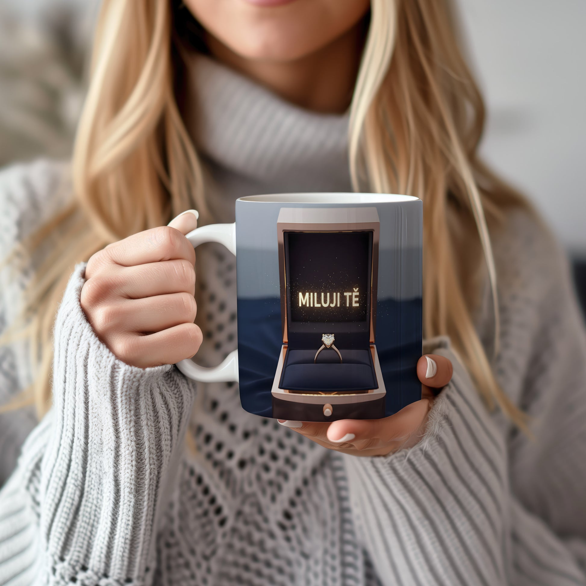 Hrnček s nápisem MILUJI TĚ a zlatým prstenem v krabičce.