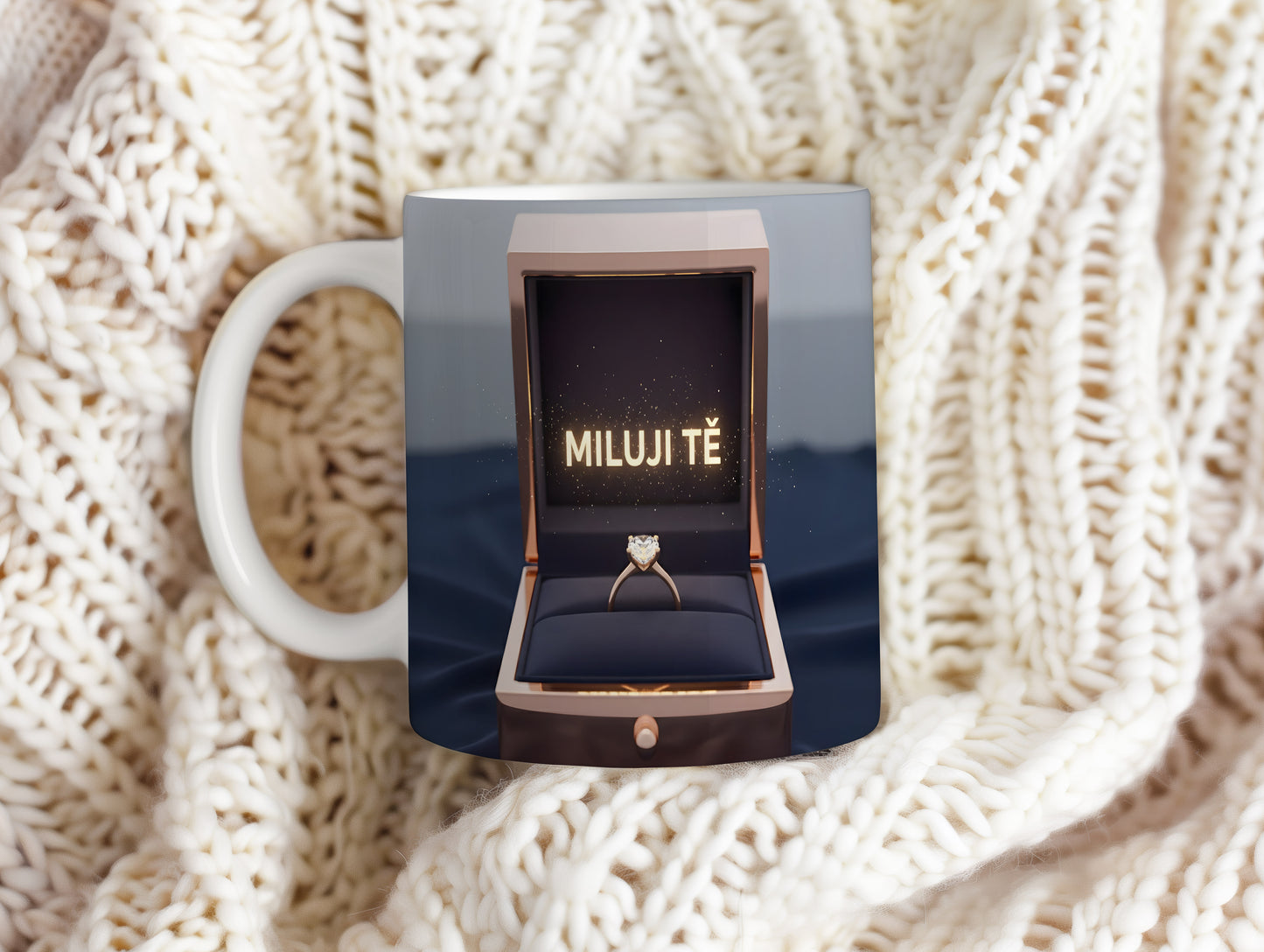 Hrnček s nápisem MILUJI TĚ a zlatým prstenem v krabičce.