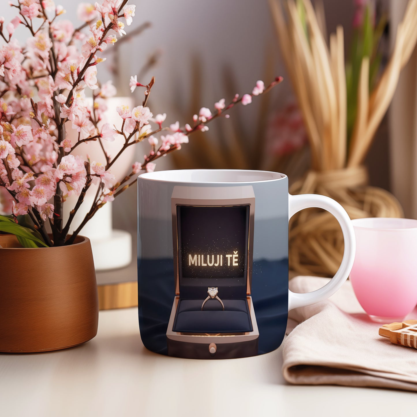 Hrnček s nápisem MILUJI TĚ a zlatým prstenem v krabičce.
