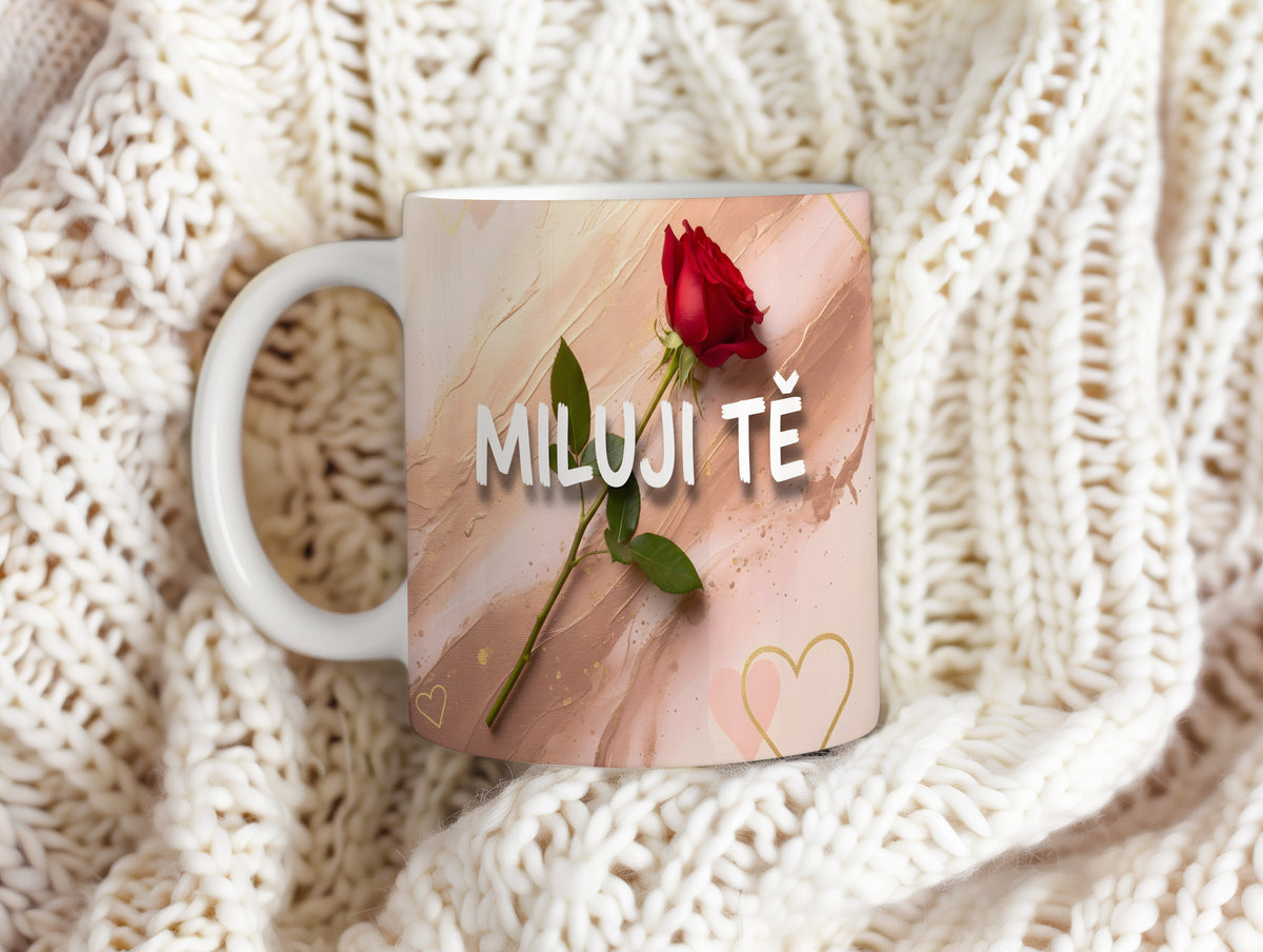 Hrnek s červenou růží a nápisem MILUJI TĚ na pastelovém pozadí.