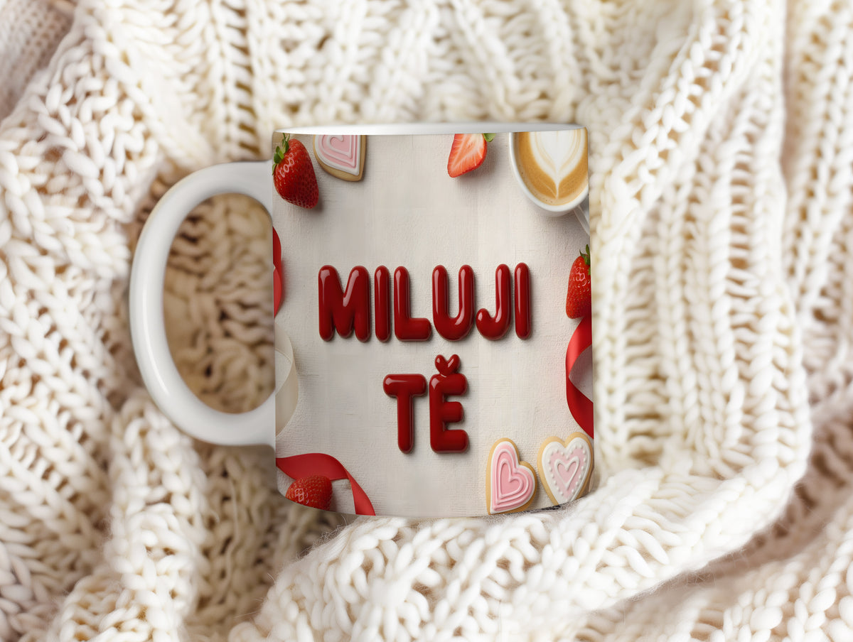 Bílý hrnek s nápisem MILUJI TĚ, ozdobený srdíčky a jahodami.