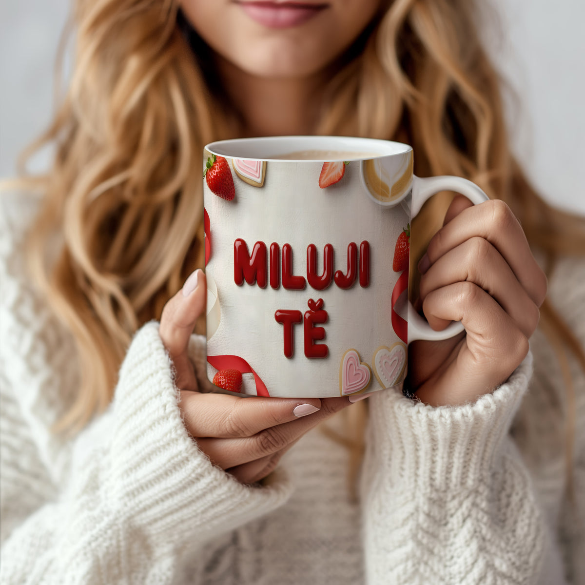 Bílý hrnek s nápisem MILUJI TĚ, ozdobený srdíčky a jahodami.