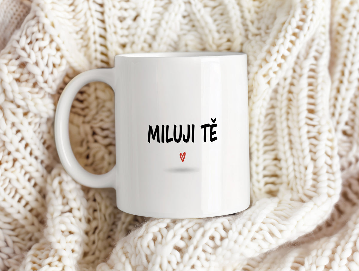 Bílý hrnek s nápisem MILUJI TĚ a červeným srdcem.