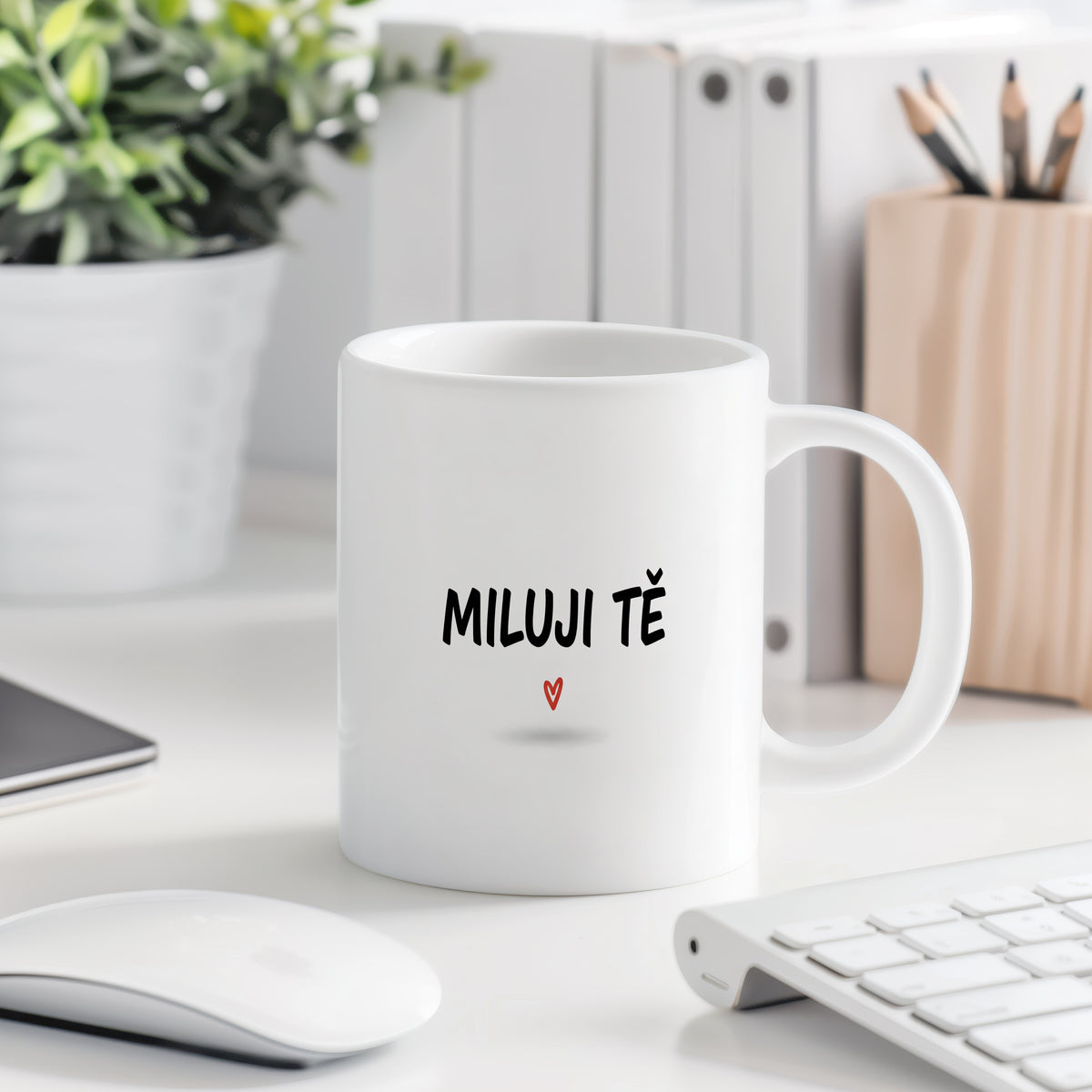 Bílý hrnek s nápisem MILUJI TĚ a červeným srdcem.