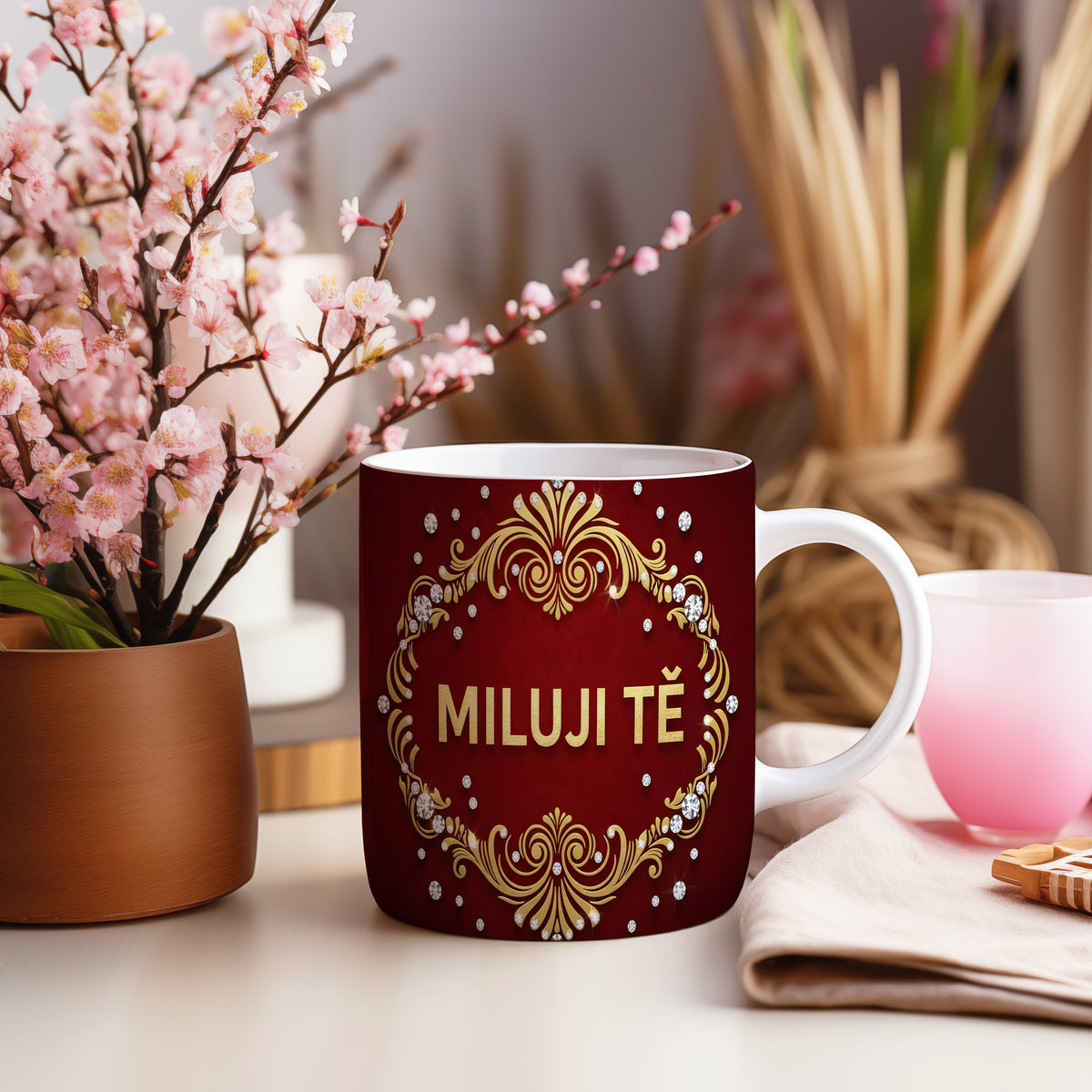 Červený hrnek se zlatými ornamenty a nápisem MILUJI TĚ.