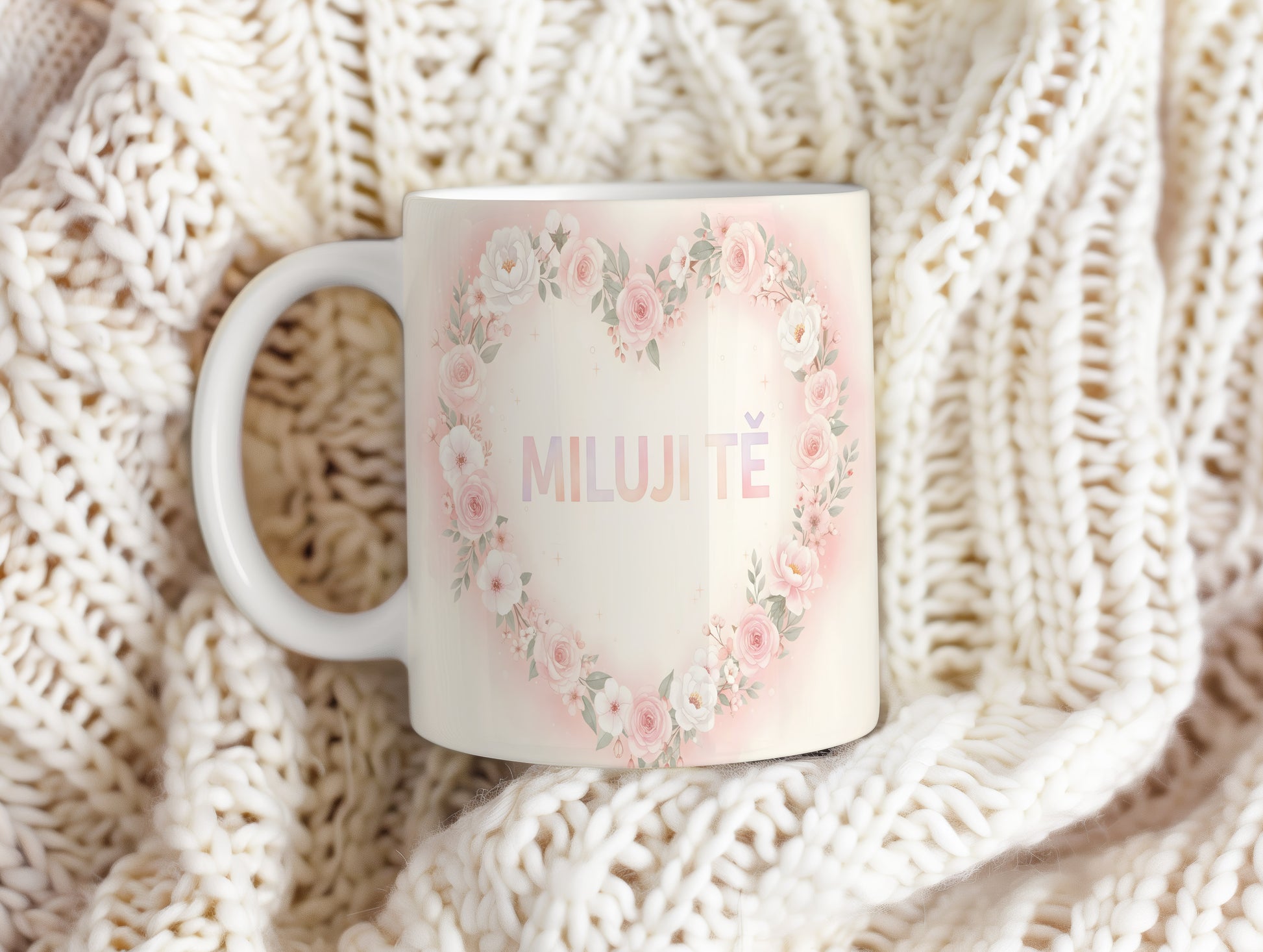 Hrnek s nápisem MILUJI TĚ a květinovým srdcem v pastelových barvách.
