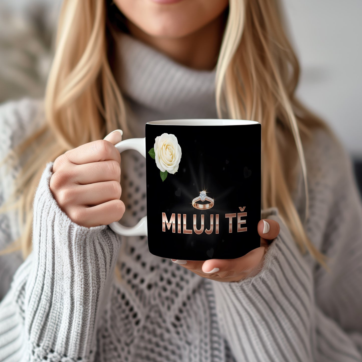 Černý hrnek s nápisem MILUJI TĚ, prstenem a bílou růží.