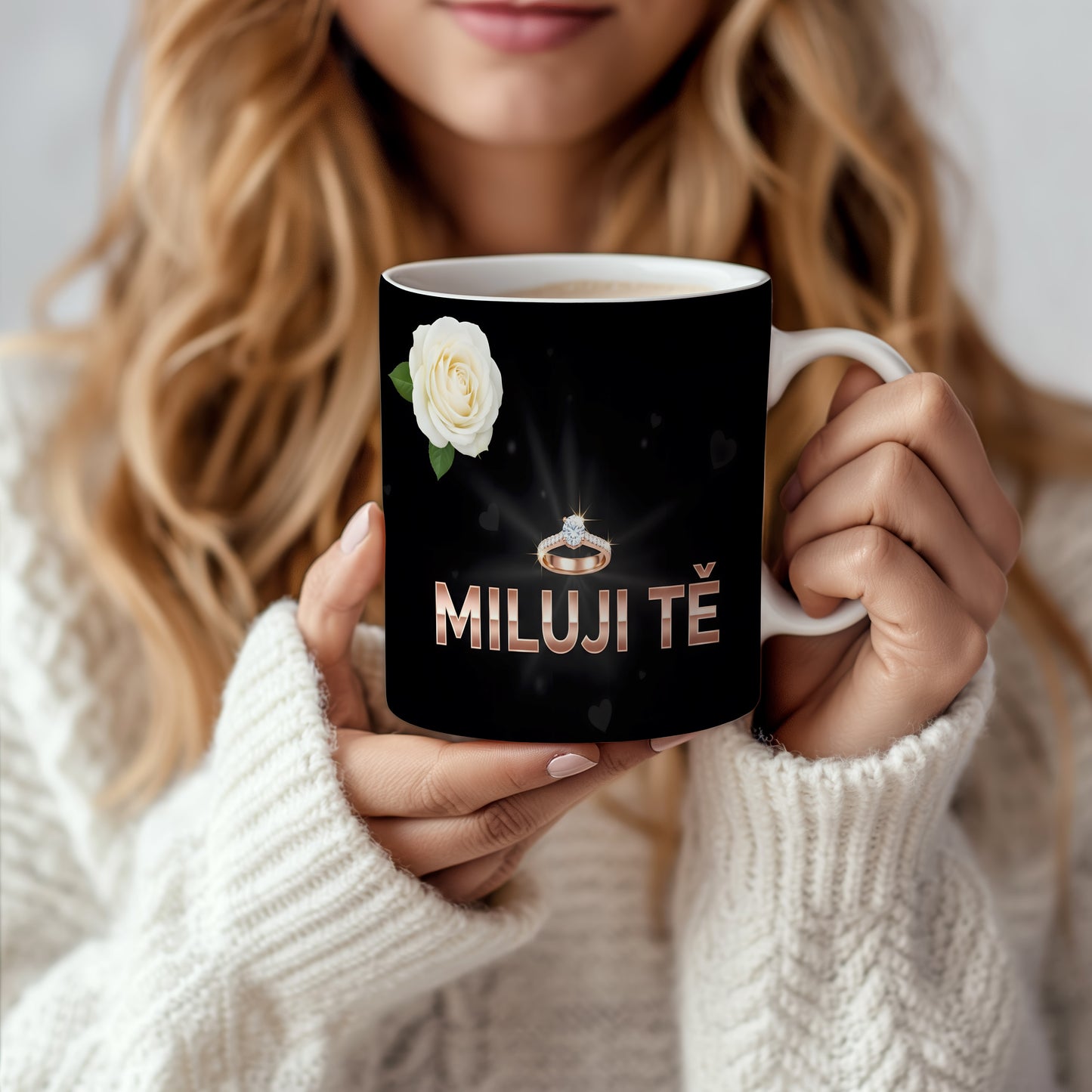 Černý hrnek s nápisem MILUJI TĚ, prstenem a bílou růží.