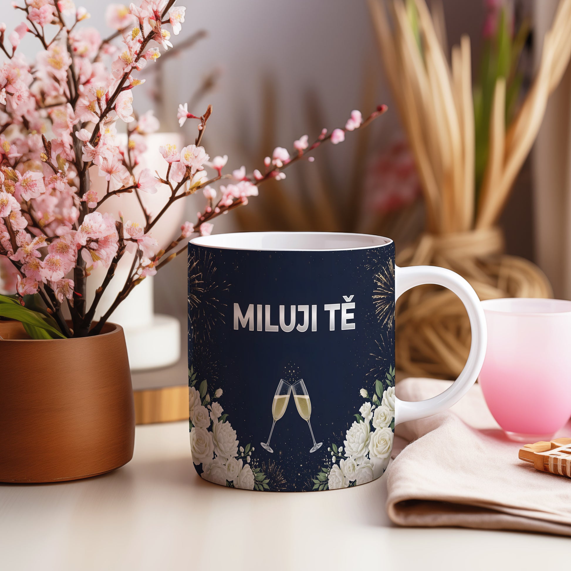 Tmavě modrý hrnek s nápisem MILUJI TĚ, květinami a skleničkami.