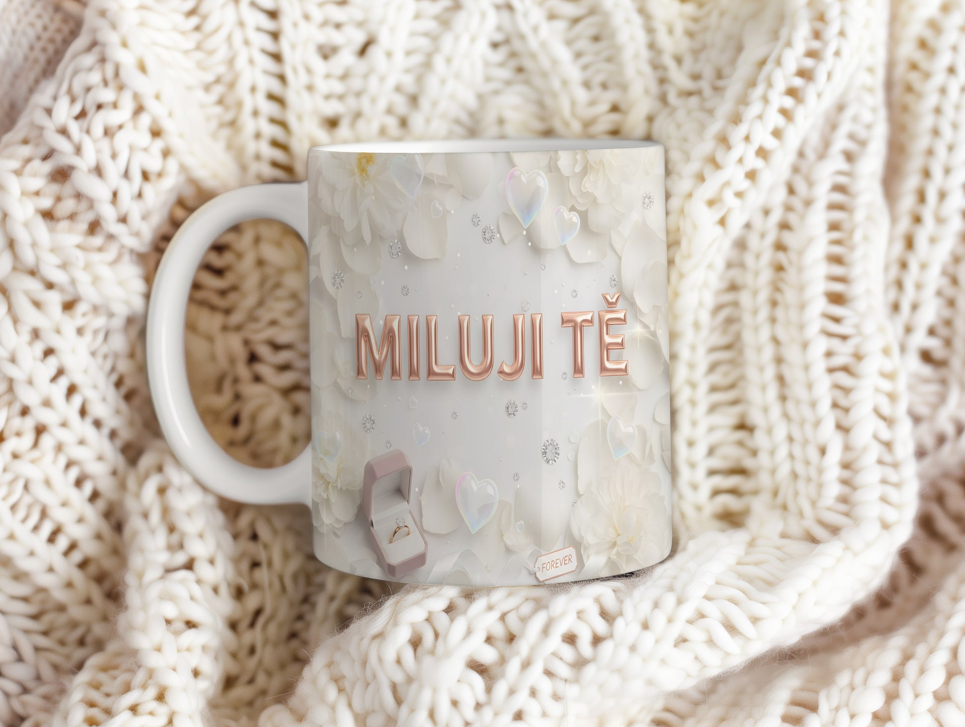 Bílý hrnek s nápisem MILUJI TĚ a květinovým motivem.
