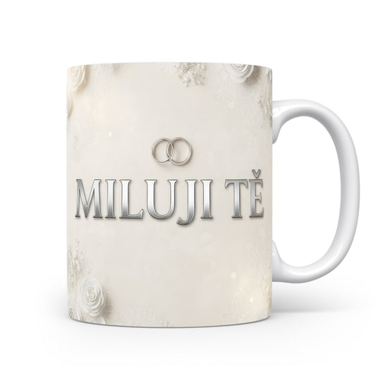 Bílý hrnek s nápisem MILUJI TĚ a květinovým motivem.