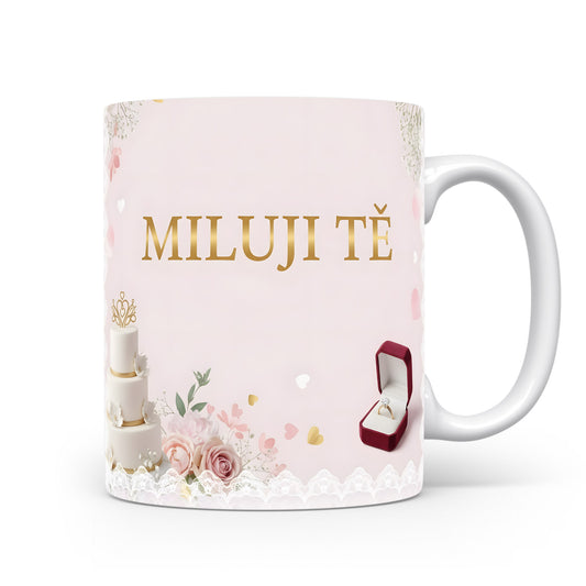 Růžový hrnek s nápisem MILUJI TĚ, květinami a prstenem.